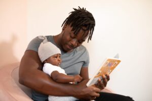 Dad reading baby a book in bed